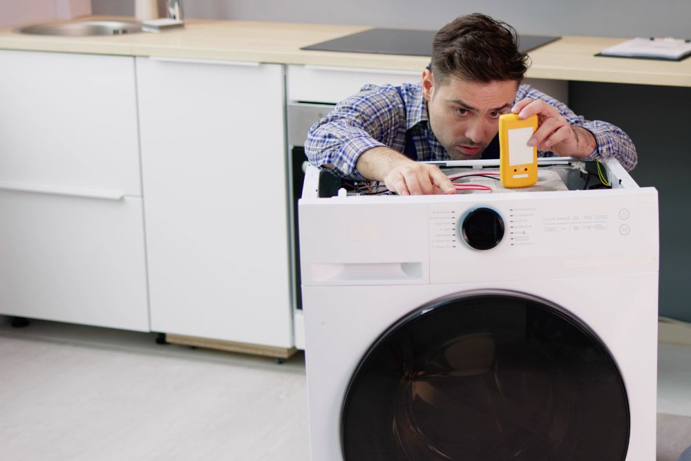 A technician works on a washing machine, highlighting laundry appliance repair services in Springfield, IL.