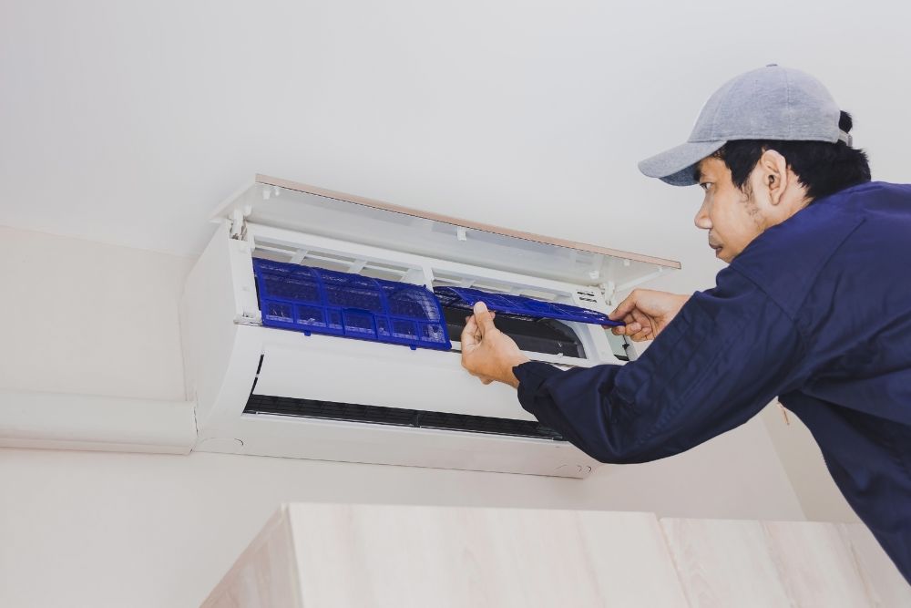 A technician is fixing an air conditioner indoors, highlighting HVAC repair services available in Springfield, IL.