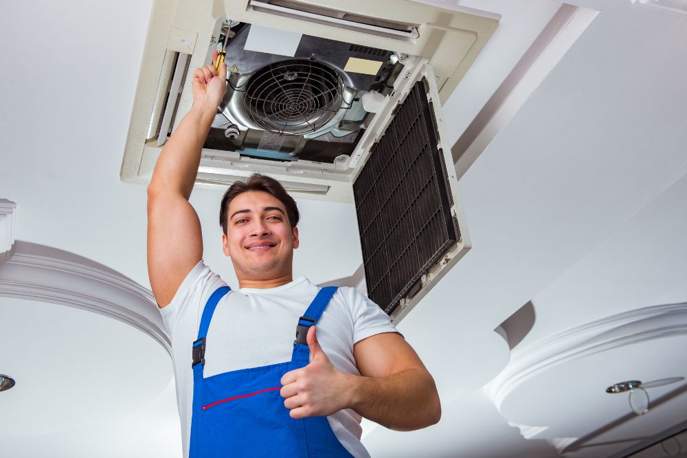 A man in overalls stands with an air conditioner, highlighting commercial appliance repair services available in Springfield, IL.