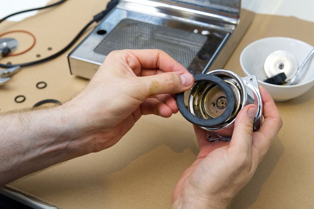 A man uses a wrench to fix a coffee maker, with appliance parts visible in a Springfield, IL repair service environment.